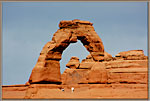 A couple stands beneath Delicate Arch